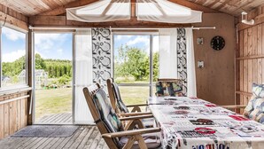 A cozy wooden cabin with a large dining table, chairs, and a view of a green landscape. - Enerhögen Flädern by Interhome (Bullaren)