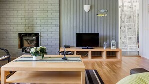 Ein modernes Wohnzimmer mit Backsteinwand, Holzpaneel und einem Fernseher auf einem Holzständer.