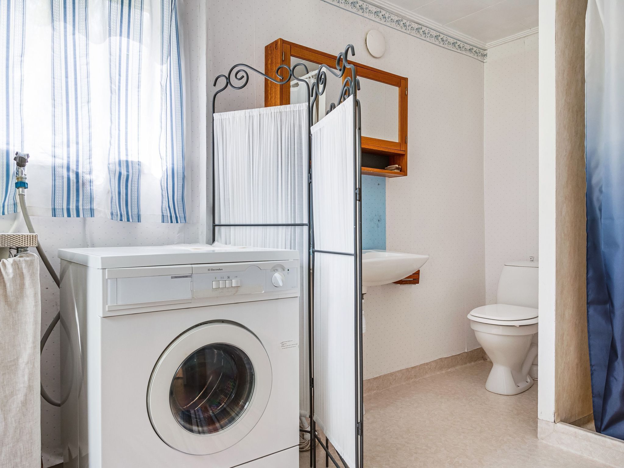A compact bathroom with a washing machine, a sink, and a toilet.