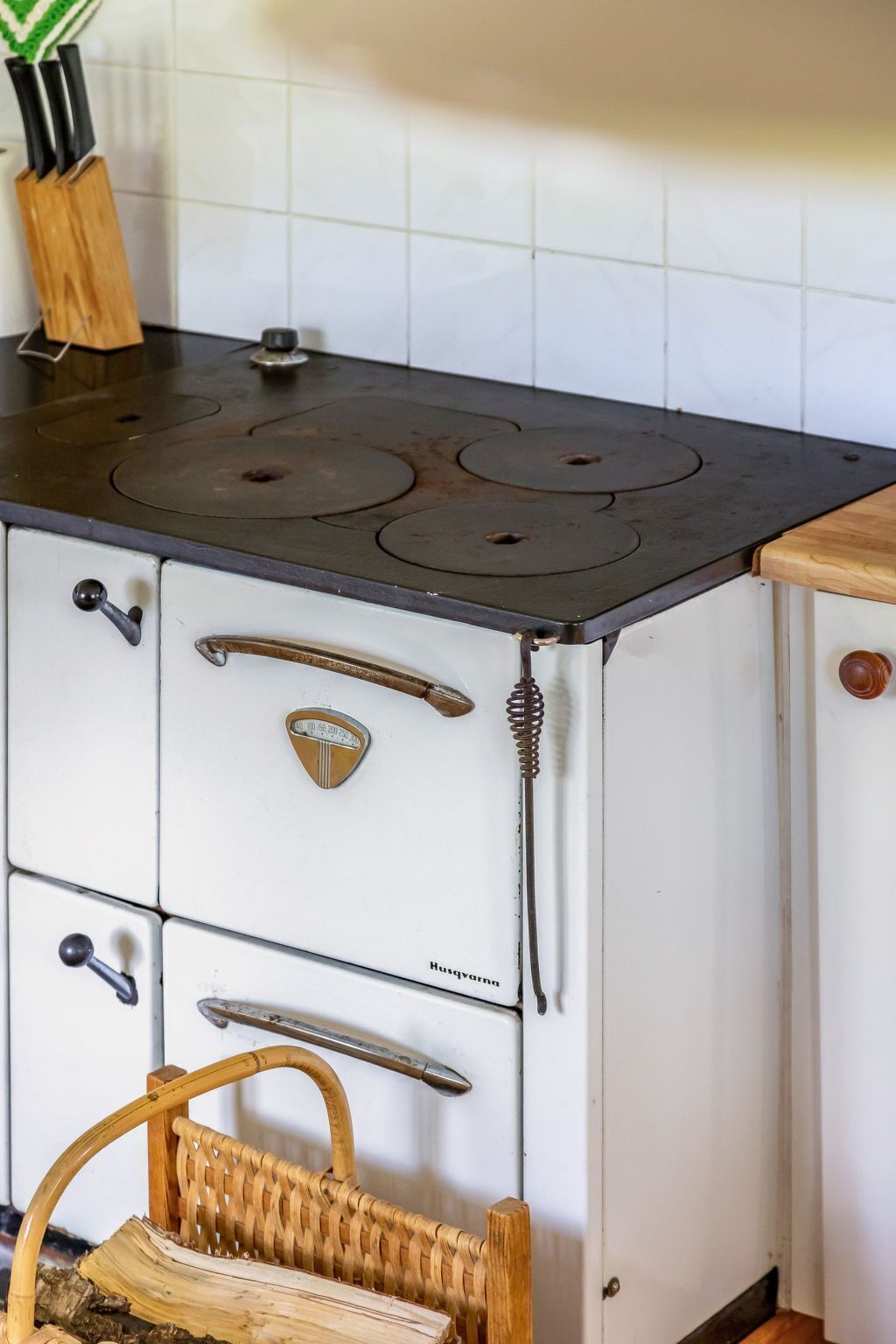 A kitchen with a stove, white cabinets, and a woven basket.