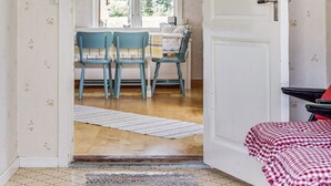 Una habitación con comedor, que incluye una mesa con sillas, una ventana con cortinas y una puerta que da a otra habitación.