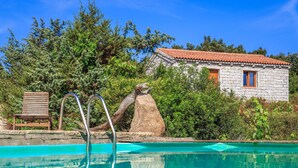 A swimming pool with a stone house in the background. - Mare di Ginepri (BAD115) by Interhome (Badesi)