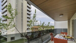 A balcony with a table set for dining, overlooking a street and buildings. - Residence Monica by Interhome (Lignano Sabbiadoro)