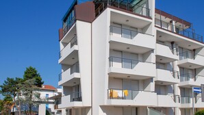 Um edifício residencial com vários andares, varandas, janelas amplas e céu claro.