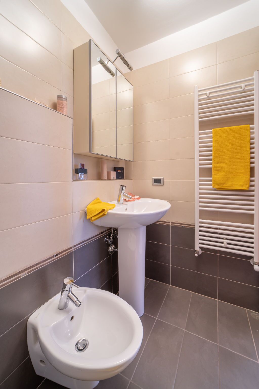 Un baño con lavamanos, espejo y toallero.