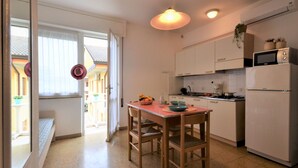 A compact kitchen with a dining table, chairs, a refrigerator, and a microwave. - Villa Gaby by Interhome (Lignano Sabbiadoro)