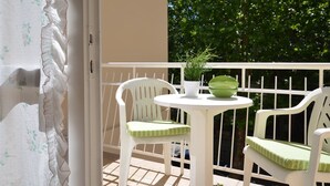 A balcony with a white table and two white chairs, a potted plant, and a green bowl. - Villa Gaby by Interhome (Lignano Sabbiadoro)