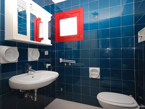 A bathroom with a white sink, a toilet, and a mirror with a red frame. - Holiday Village by Interhome (Lignano Sabbiadoro)