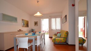 Een eethoek met een tafel, stoelen, een bank en een televisie.