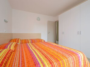 Un dormitorio con una cama grande, un armario y una puerta que da a otra habitación.
