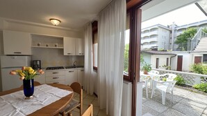 A kitchen with white cabinets, a dining table with chairs, and a vase of flowers.