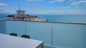 A balcony with a view of the sea and a building with a flagpole.