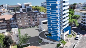 A modern high-rise building with a blue facade, surrounded by other residential buildings and a clear view of the sea. - Nashira by Interhome (Lignano Sabbiadoro)