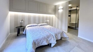 A modern bedroom with a bed, bedside tables, and a walk-in closet.