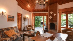 A cozy living room with a wooden ceiling, a fireplace, a dining table, and a sofa. - Villa Ralph by Interhome (Lignano Riviera)