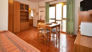 Un espace de vie compact comprenant un coin repas, une kitchenette et un téléviseur.