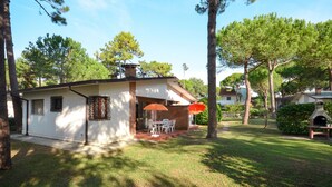 Une petite maison de plain-pied dotée d’une terrasse et d’un espace extérieur aménagé pour s’asseoir.