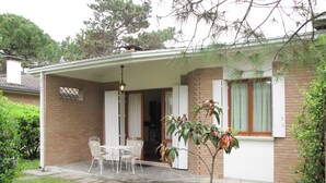 Een gelijkvloers huis met een overdekte patio, een bakstenen gevel en een kleine tuin.