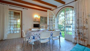A dining area with a table set for four, surrounded by chairs, and a sofa in the foreground.