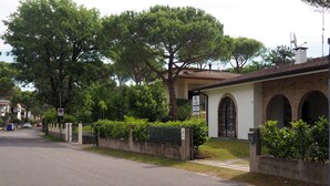 A street view with a building featuring a tiled roof, arched windows, and a sign indicating a European location.