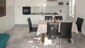 Cozinha moderna com armários brancos, coifa de aço inoxidável e micro-ondas sobre a bancada.