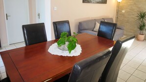 Un comedor con mesa de madera, sillas negras, un sofá gris y una planta en maceta.