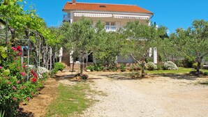 A building with a red-tiled roof, surrounded by a garden with various plants and flowers. - Apartment Matius by Interhome (Rab/Rab)