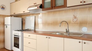 A kitchen with beige cabinets, a stainless steel sink, a gas stove, and a refrigerator. - Apartment Matius by Interhome (Rab/Rab)