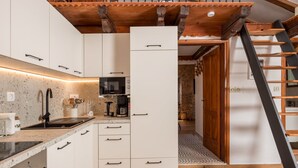 A modern kitchen with white cabinets, a built-in microwave, and a wooden staircase. - Apartment Mia by Interhome (Krk/Malinska)