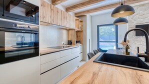 Une cuisine moderne avec des meubles en bois, un four encastré et un grand îlot central doté d’un évier.