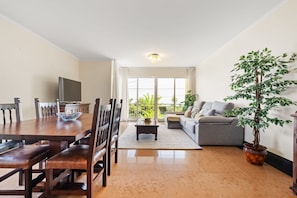 A dining area with a wooden table and chairs, a coffee table, and a television. There is a sofa and a potted plant in the living area. - Casa D Agostinha by Homie (Ponta do Sol)