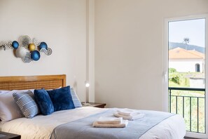 A neatly made bed with a striped bedspread, a wooden headboard, and a nightstand with a lamp. - Casa D Agostinha by Homie (Ponta do Sol)