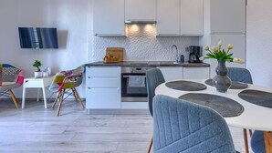 Eine moderne Küche mit weißen Schränken, einem eingebauten Ofen und einem Essbereich mit weißem Tisch und blauen Stühlen.
