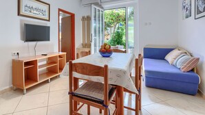 A modern living room with a dining table, chairs, a blue sofa, and a TV.