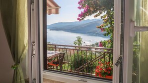 A balcony with a table and chairs, overlooking a body of water and mountains. - Apartment Neda by Interhome (Rabac)