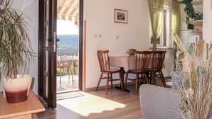 A dining area with wooden chairs and a table, a potted plant, and a view of the outdoors. - Apartment Neda by Interhome (Rabac)