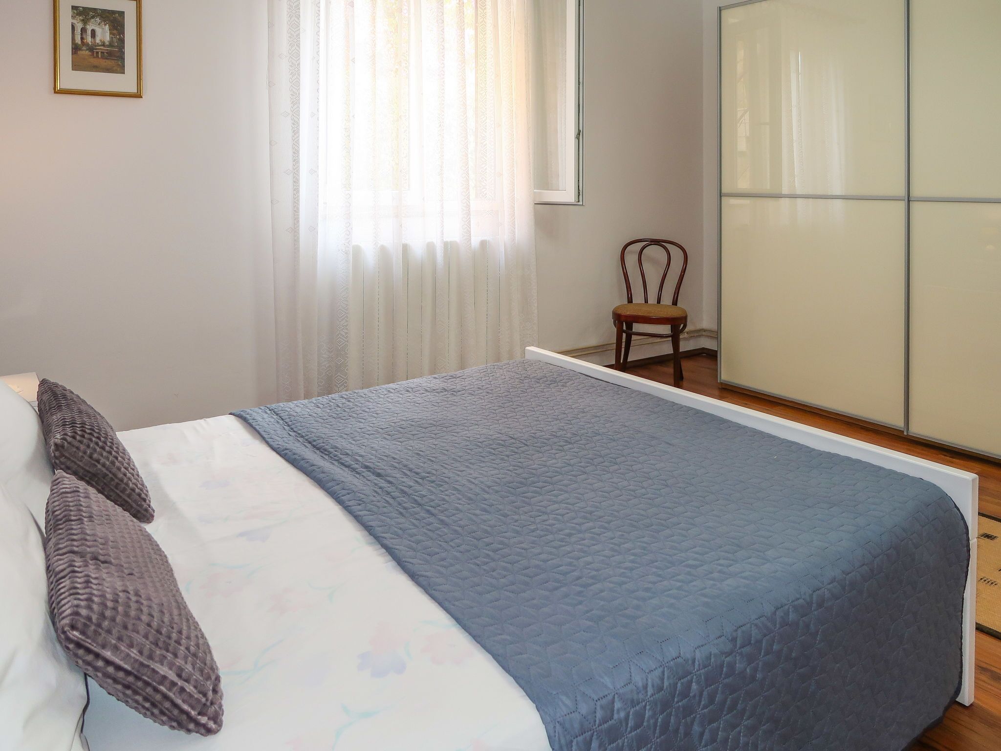 Una camera da letto con un letto, una sedia, un armadio e una finestra con tende.