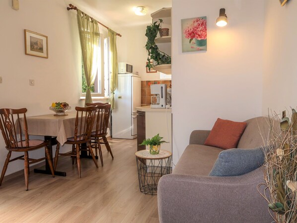 A cozy living room with a sofa and a dining area with wooden chairs and a table. - Apartment Neda by Interhome (Rabac)