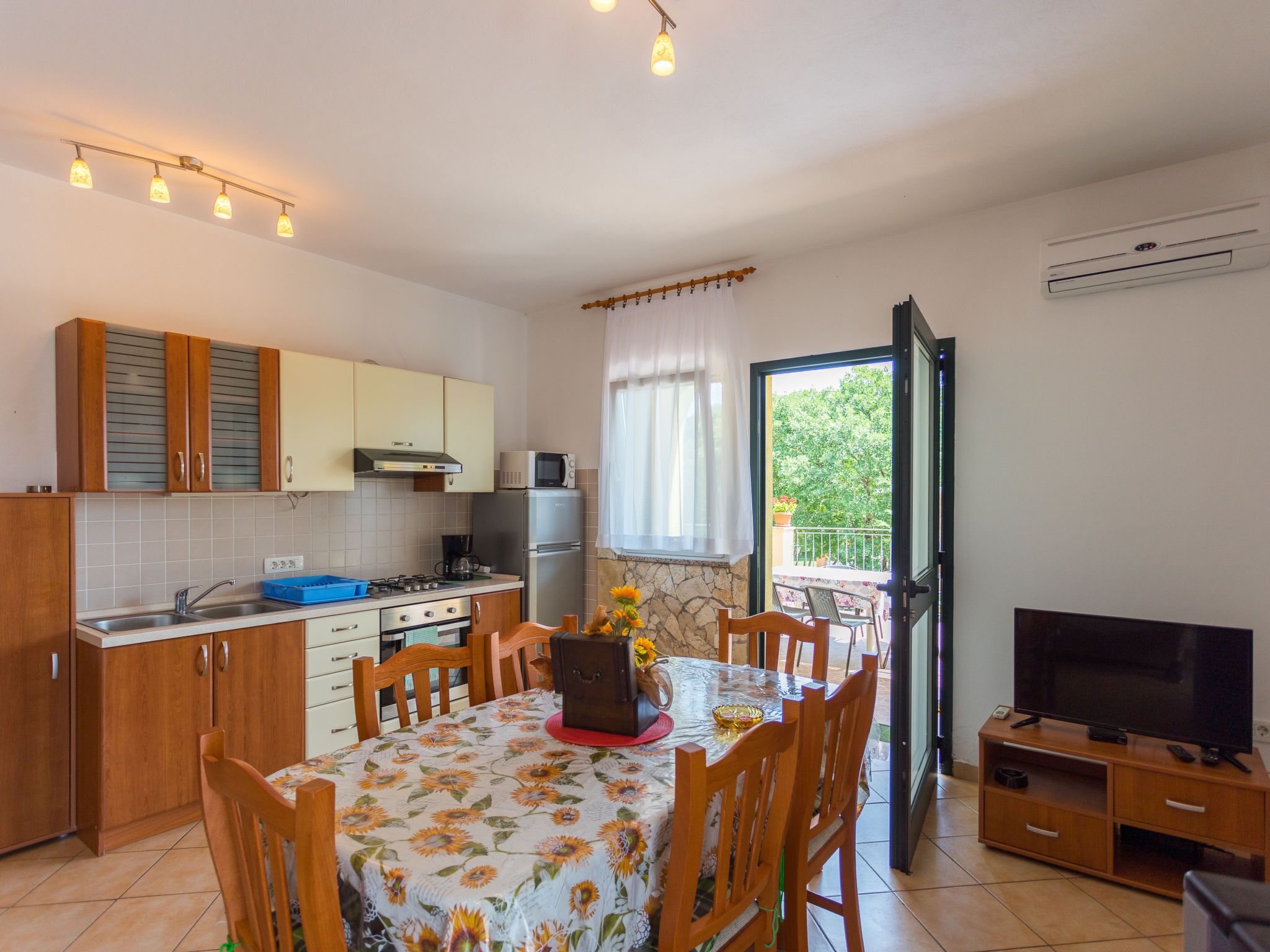 Een compacte keuken met een eetgedeelte, een televisie en een balkon met uitzicht.