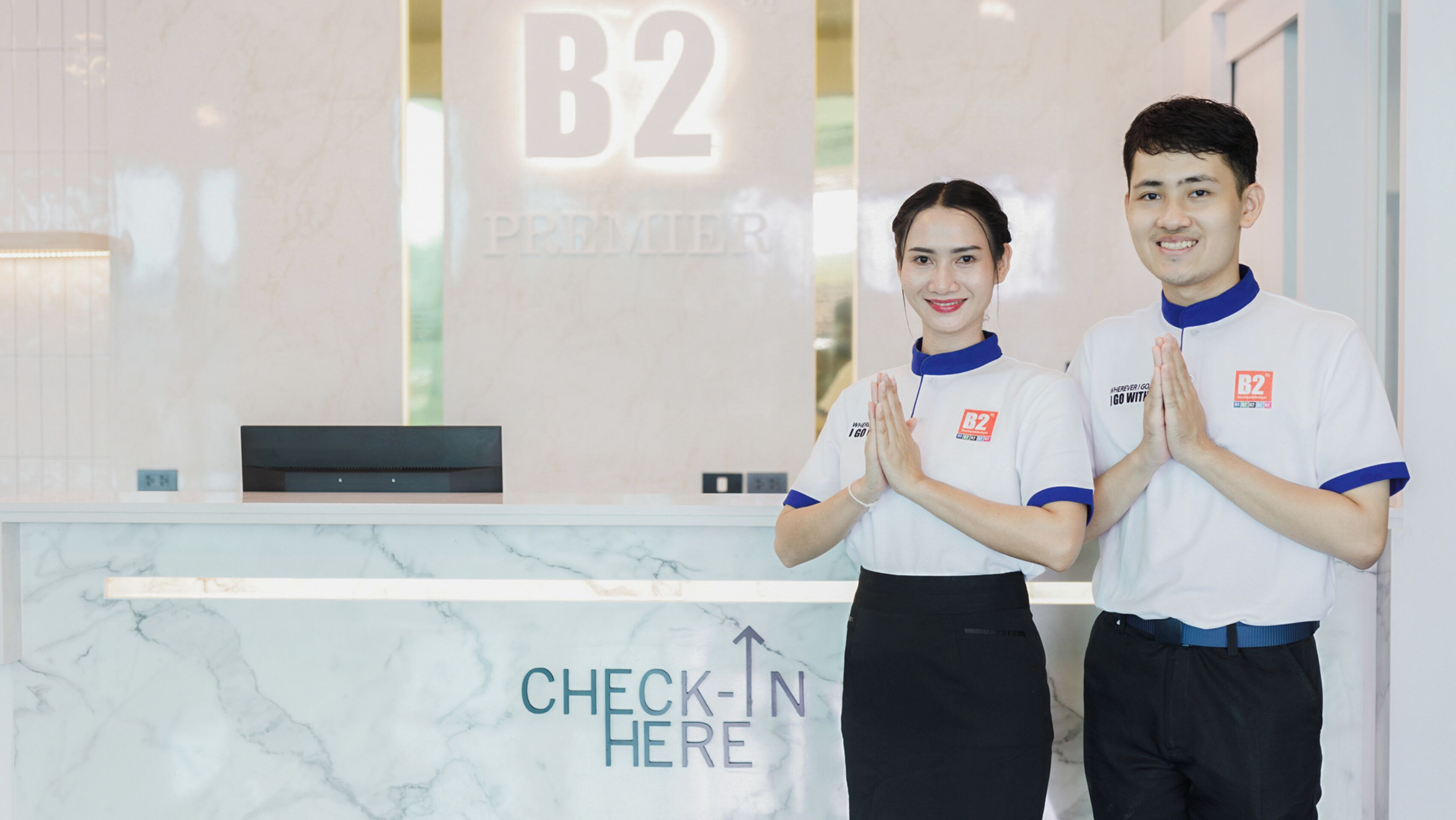 A reception desk with a marble surface and a sign that reads "CHECK-IN HERE".