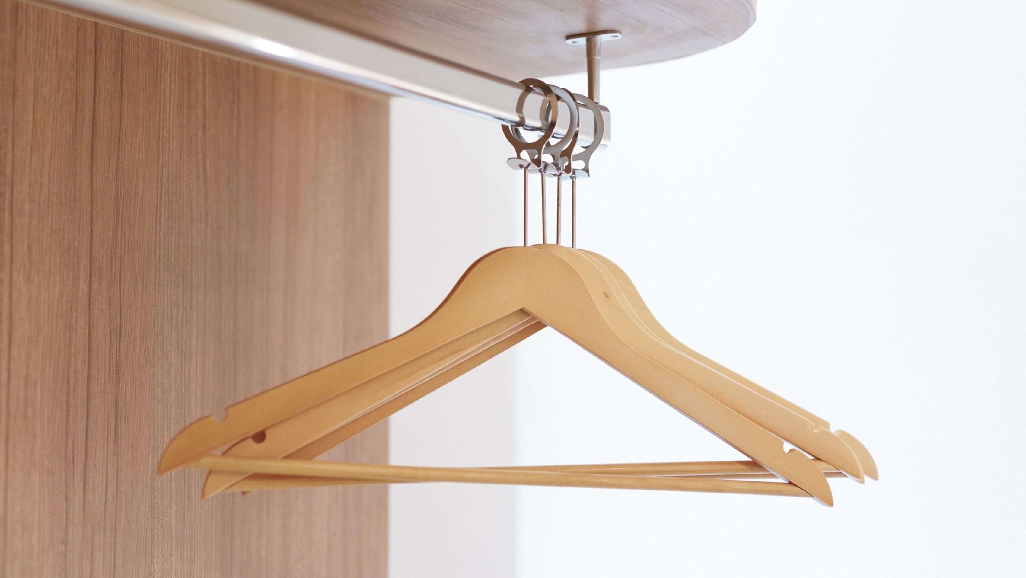 A wooden hanger suspended from a ceiling-mounted rod.