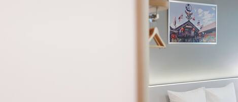 A hotel room with a bed, a bedside table, and a wall-mounted picture of a building with flags.