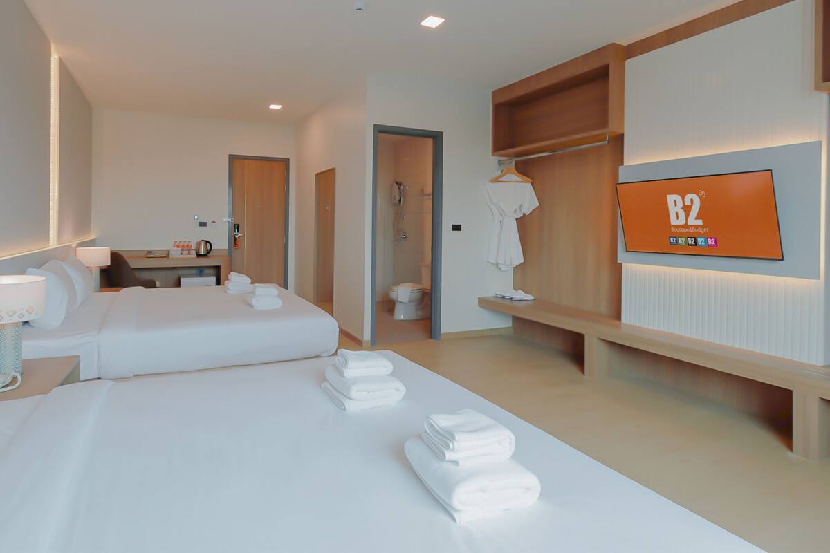 Habitación de hotel con dos camas, un escritorio, un televisor y baño.