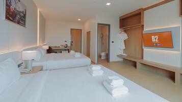 Habitación de hotel con dos camas, un escritorio, un televisor y baño.