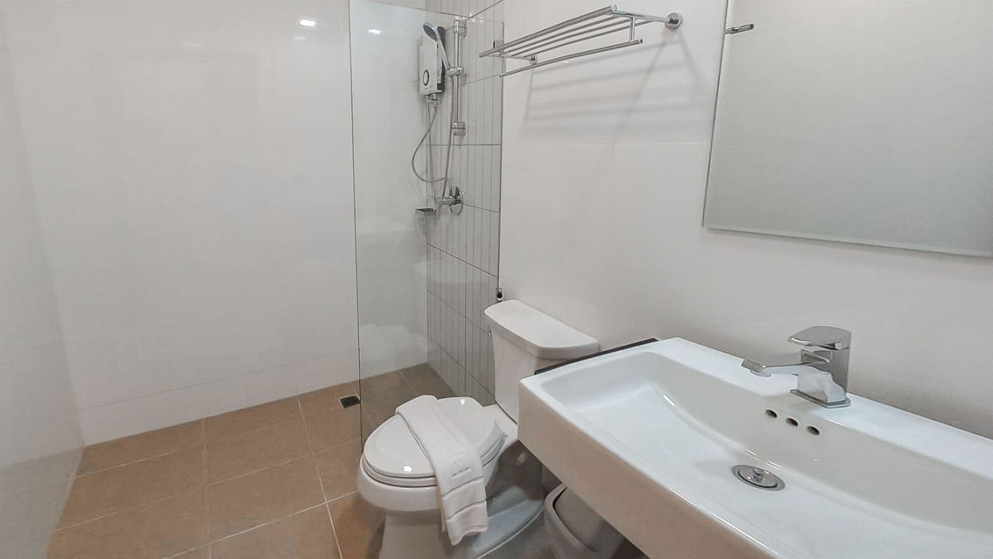 A modern bathroom with a glass-enclosed shower, a toilet, and a sink with a mirror above it.