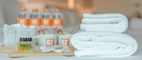 A neatly arranged bathroom with a stack of white towels, a bottle of shampoo, and several bottles of B2 shampoo.