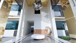 A modern building with a central open space, patterned floor, and a hanging decorative element. - B2 Udon Premier Hotel (Udon Thani)