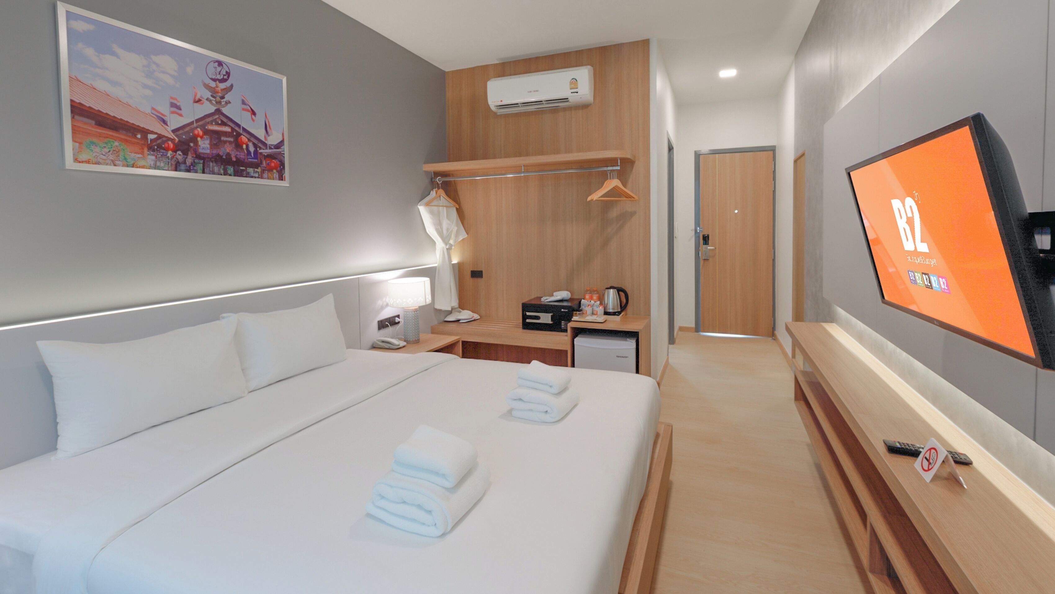 A modern hotel room with a large bed, a TV, a desk, and a wardrobe.