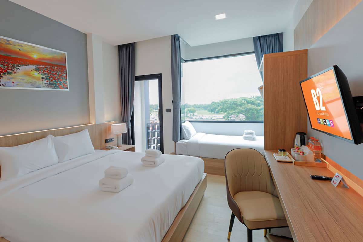 Habitación de hotel con una cama grande, un escritorio con ordenador, televisión y un cuadro en la pared.