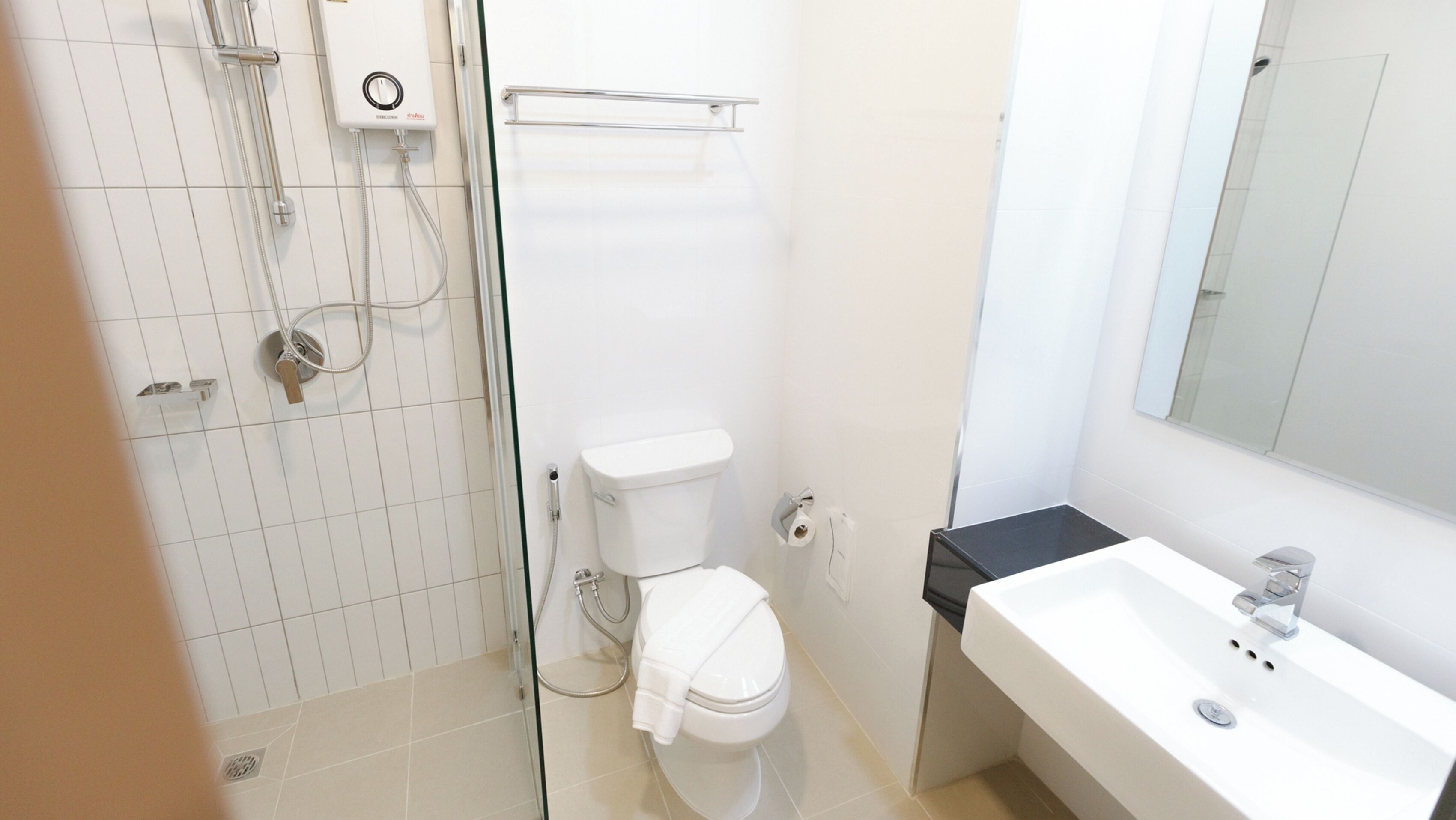 Een moderne badkamer met toilet, douche en wastafel.